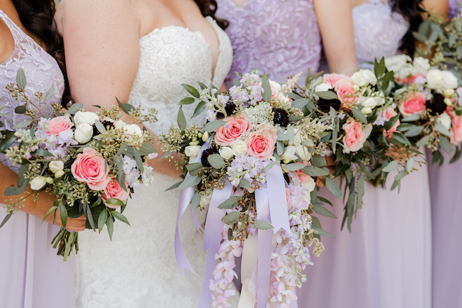 The bride and her bridesmaid's bouquets with greenery, white, pink and purple florals. 
