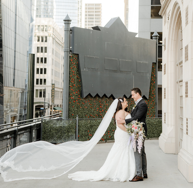 The bride and groom looking at each other with the bride's veil flowing in the wind on the wraparound terrace at the historic Crystal Ballroom at the Rice. 