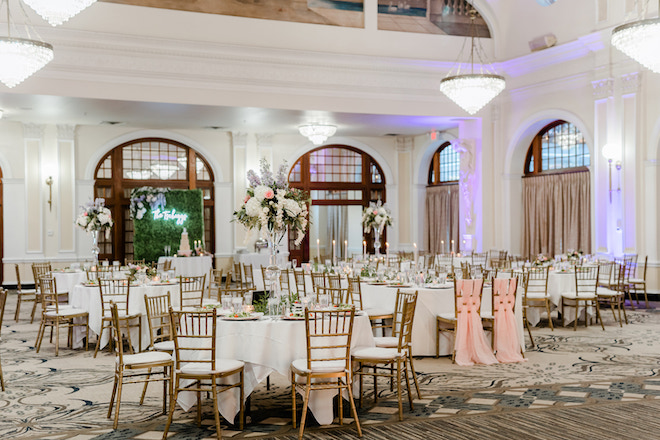 The historic Crystal Ballroom at the Rice decorated with white linen tables, candles and large floral centerpieces for a reception. 