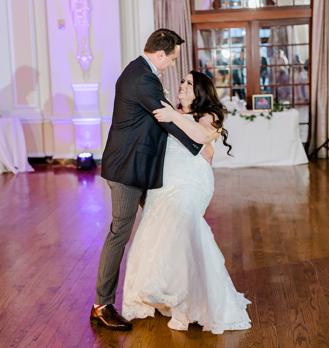 The groom dipping the bride during their first dance in a historic ballroom. 
