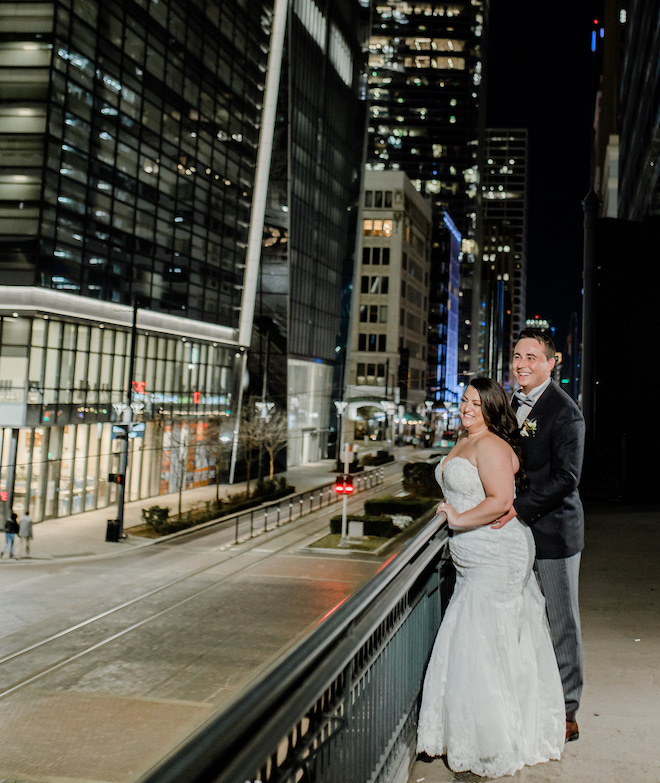 The bride and groom smiling looking at the downtown views on the terrace at Crystal Ballroom at the Rice.