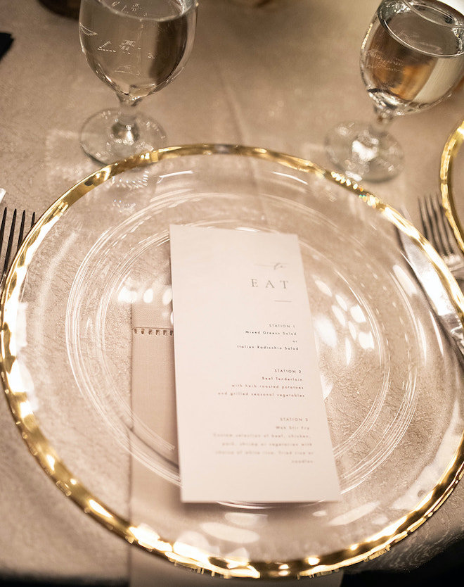 A white menu sitting on a glass plate with a gold rim.