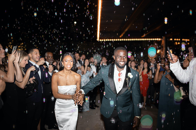 The bride and groom holding during their bubble send-off. 