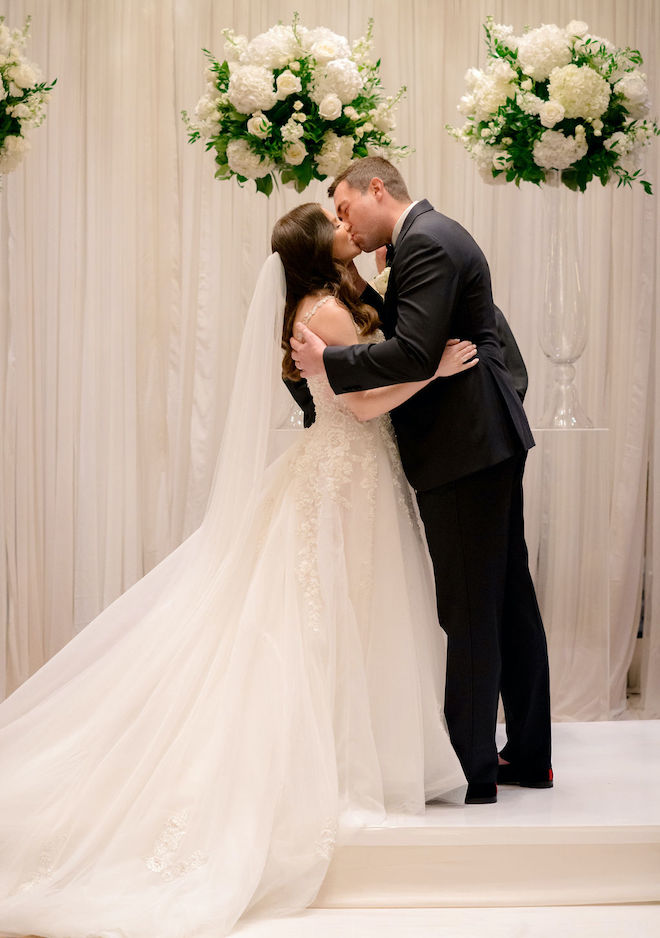 The bride and groom kiss at the altar after the wedding ceremony. 