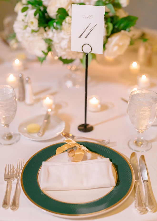 Green and gold detailed dining wear and silverware set the reception tables for guests. 