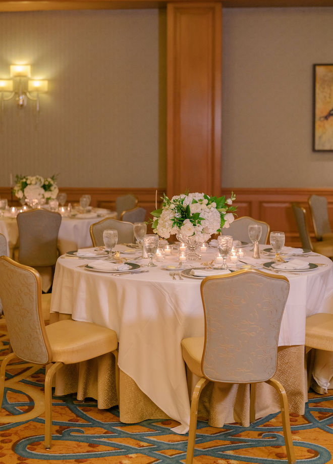 Warm candle lighting and white hydrangeas decorate the tables for the wedding reception. 