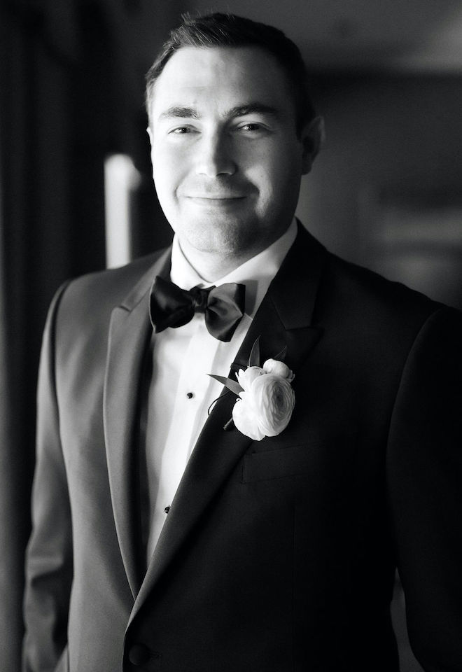 A black and white photo of the groom smiling and wearing his tuxedo for his ballroom wedding celebration. 