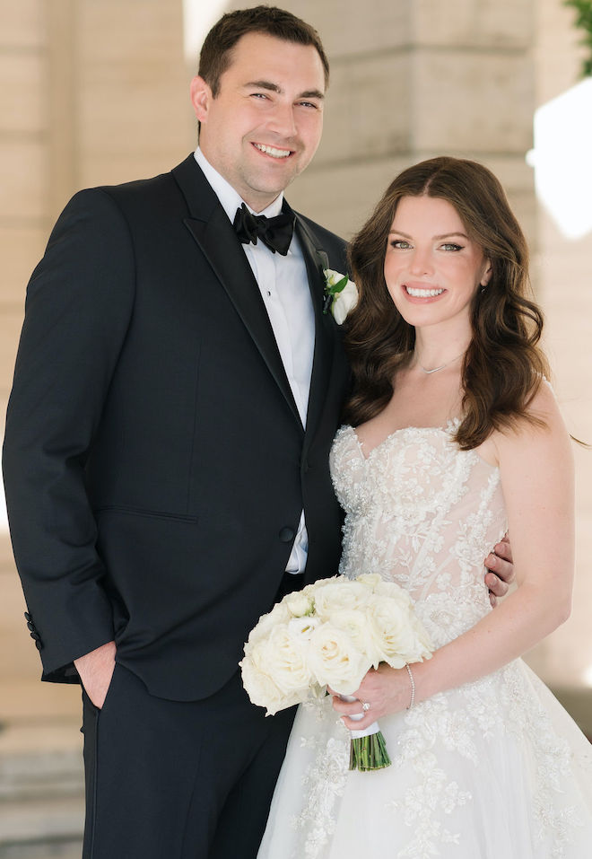 The bride and groom smile and pose outside their hotel wedding venue in Houston, Texas.