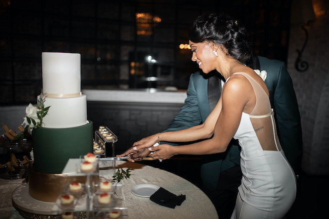 The bride and groom cutting an emerald and champagne wedding cake. 