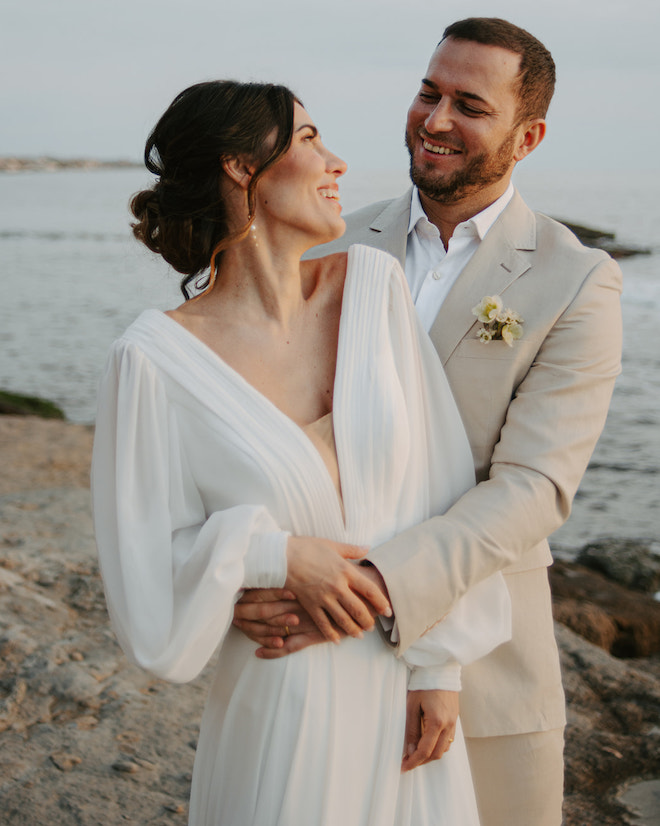 The bride and groom looking at eachother smiling during their intimate beach elopement. 