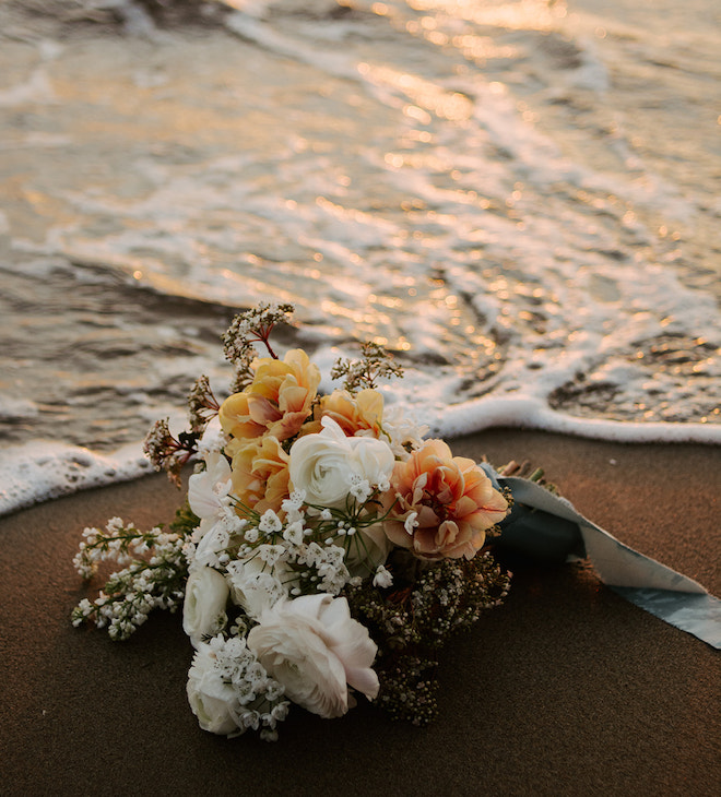A bouquet of white and muted peach florals on the shore.