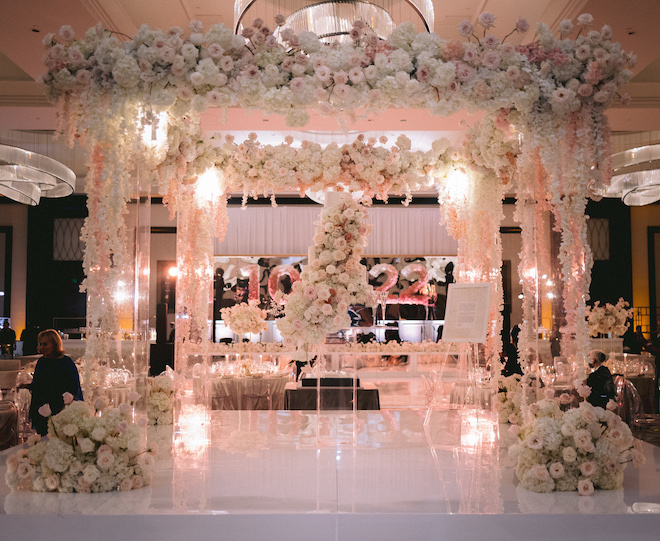 Plexi chuppah decorated with event lighting by Bright Star Productions and pink and white flowers at a ballroom wedding at Post Oak at Uptown Houston.