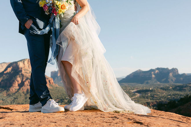 The bride and groom wearing white tennis shoes with their wedding attire. 