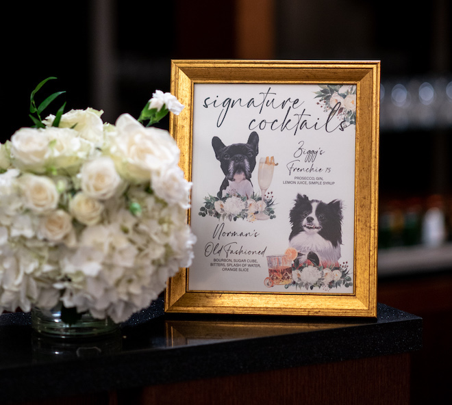 A framed signature cocktail menu with the couple's dogs on them. The cocktails are "Ziggy's Frenchie 75" and "Norman's Old Fashioned."