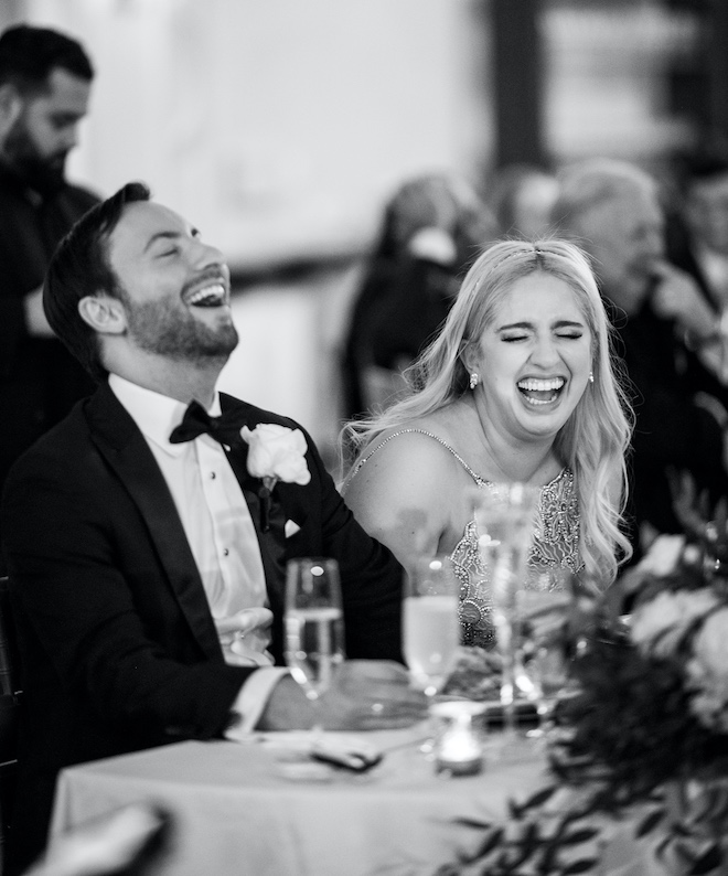 The bride and groom laughing at the reception table. 