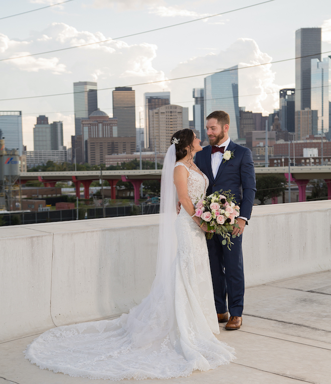 Bride and groom standing on the roof of Saint Arnold Brewery with the houston downtown skyline behind them.