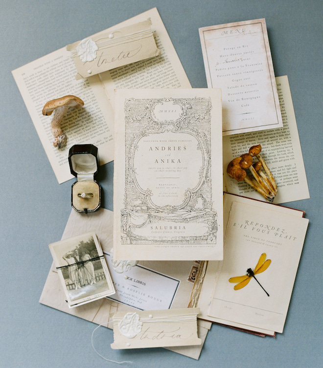 A white and cream invitation suite on torn book pages for an intimate wedding editorial by Sean Thomas Photography.