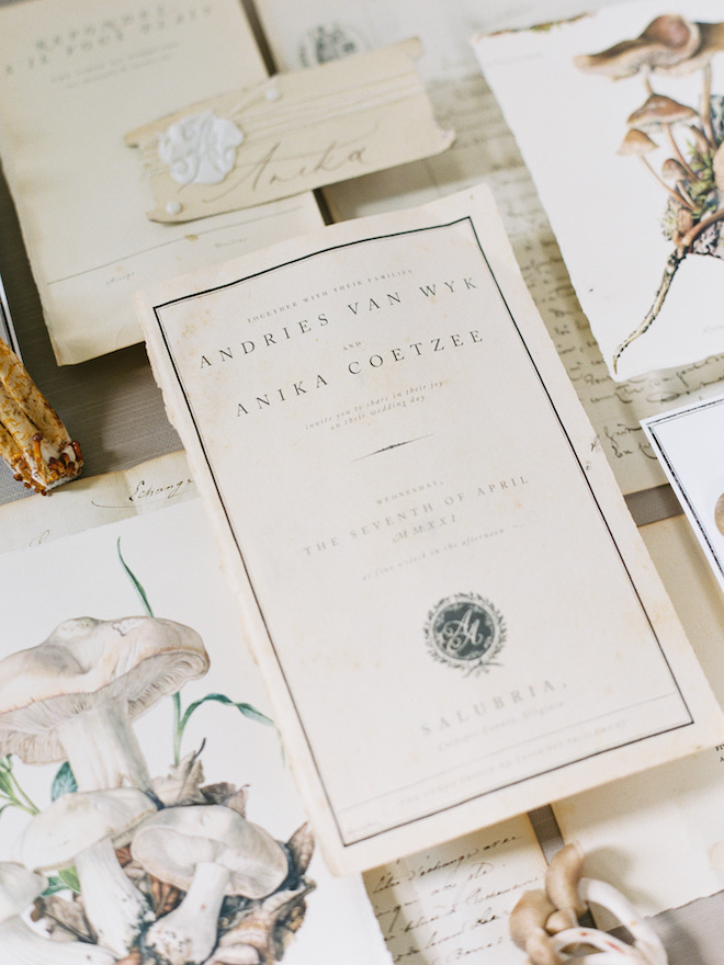 A white and cream invitation suite on torn book pages for an intimate wedding editorial by Sean Thomas Photography.