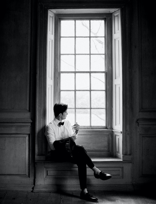 A groom sitting on a window ledge looking outside at Salubria Manor.