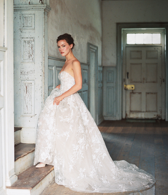 A bride in a strapless lace wedding gown walking up a step in Salubria Manor. 