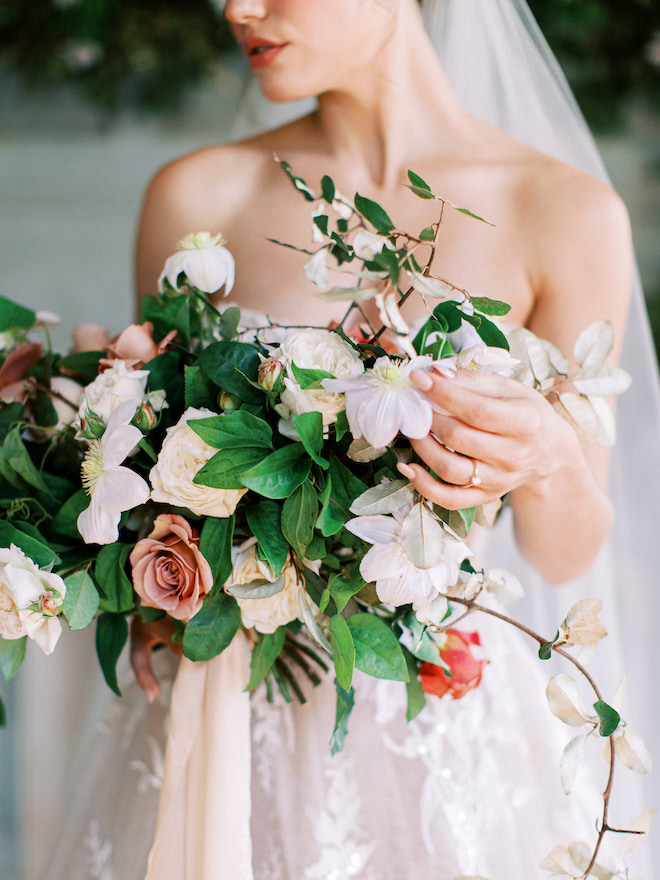 A bride holding a bouquet of greenery, white and blush florals. 