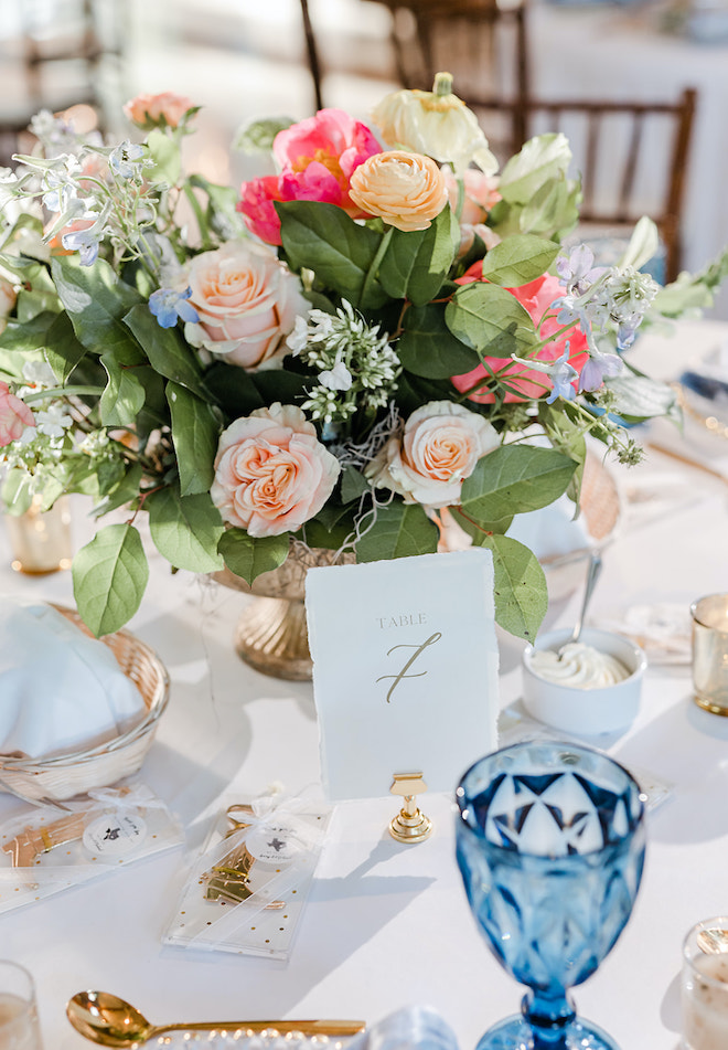 Pastel florals and gold and blue colors detail the tablescapes at the wedding reception.