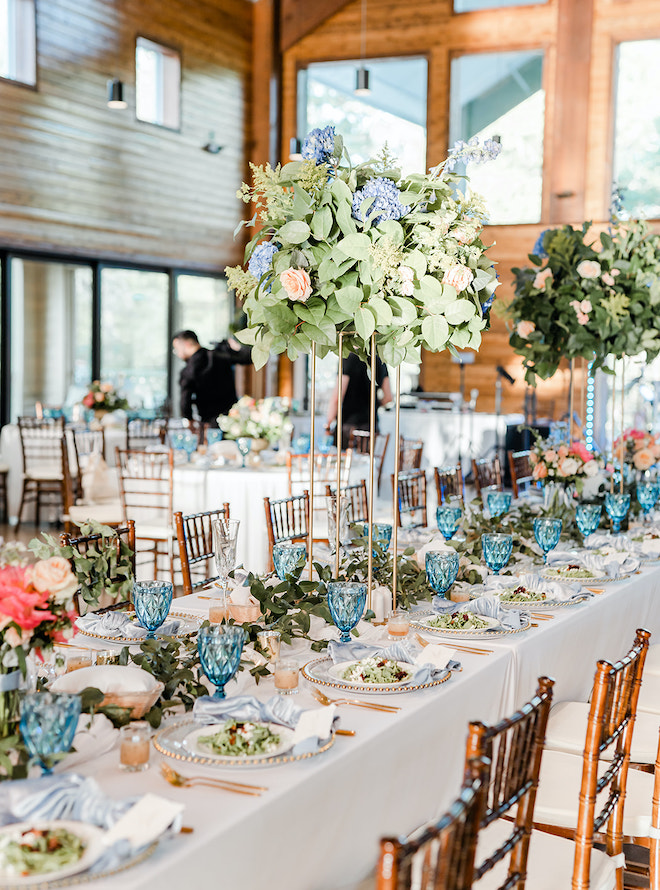 Pastel florals and gold and blue colors detail the tablescapes at the wedding reception for the wedding party table. 