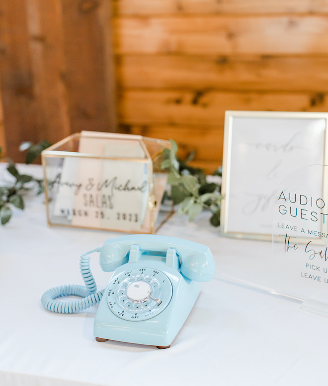 At the wedding reception, a blue telephone sits on a table for guests to leave messages on the audio guestbook for the bride and groom.