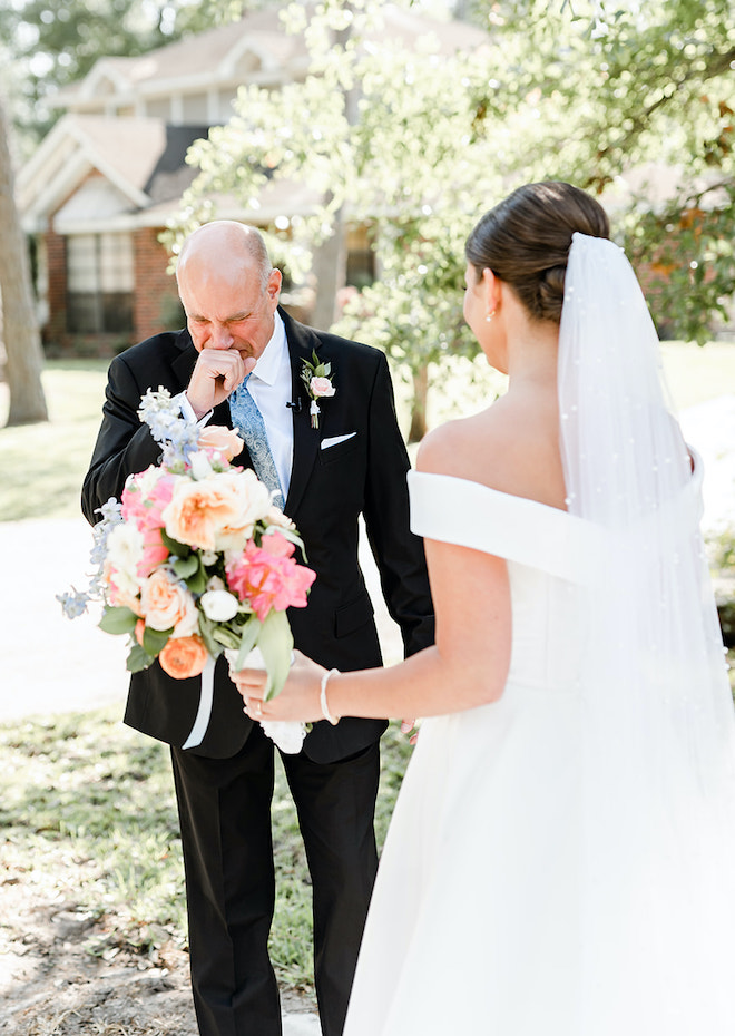 The picture displays an emotional first look between the bride and her father before walking down the aisle. 