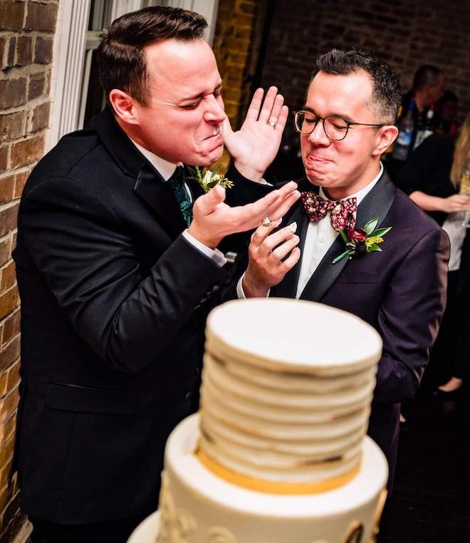 The two grooms share an intimate and memorable moment as they enjoy a taste of their wedding cake.