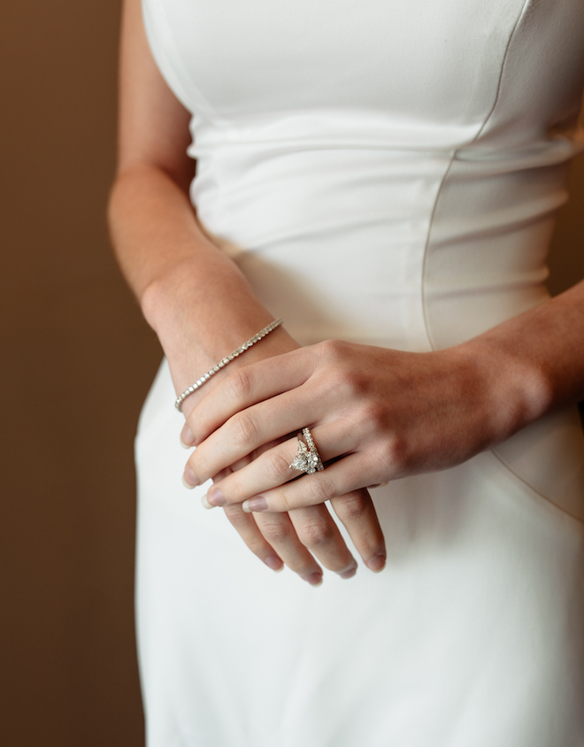 The brides wearing a simple white gown showing off her diamond tennis bracelet, pear-shaped engagement ring and diamond band from I W Marks Jewelers. 