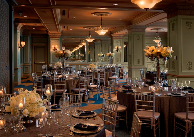 The green ballroom decorated with round tables, florals and candlelight. 