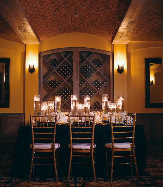 A table decorated with candles and florals in the wine vault.