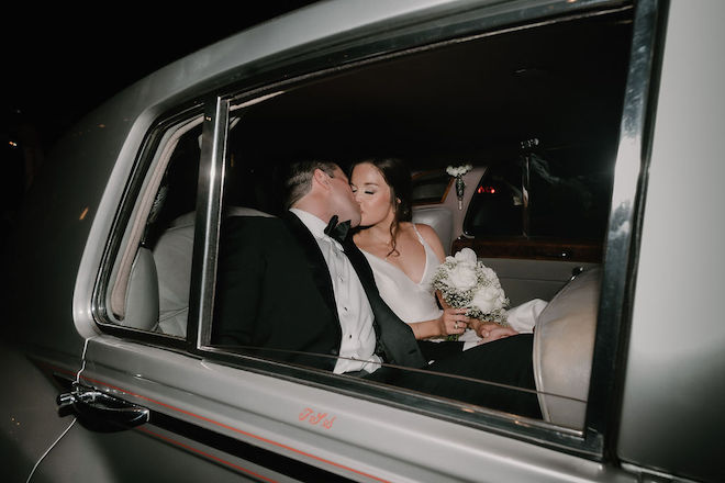 The bride and groom kissing in a vintage car. 