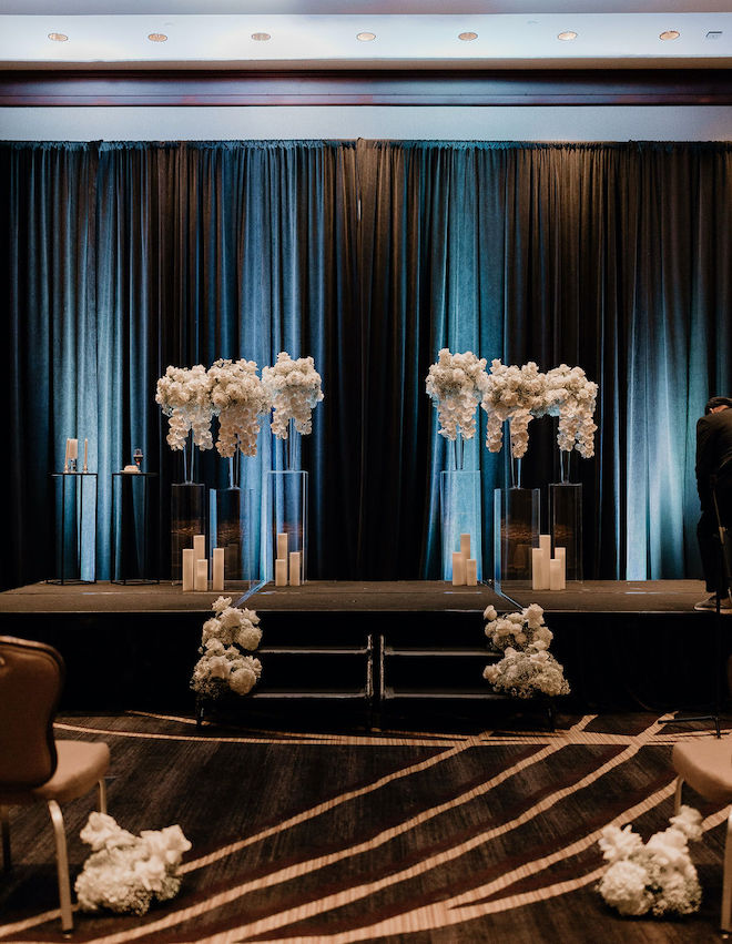 The ballroom ceremony space decorated with white florals and candles. 