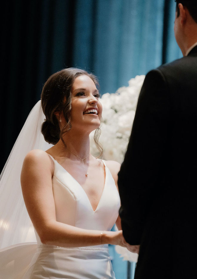 The bride smiling at the groom during their wedding ceremony. 