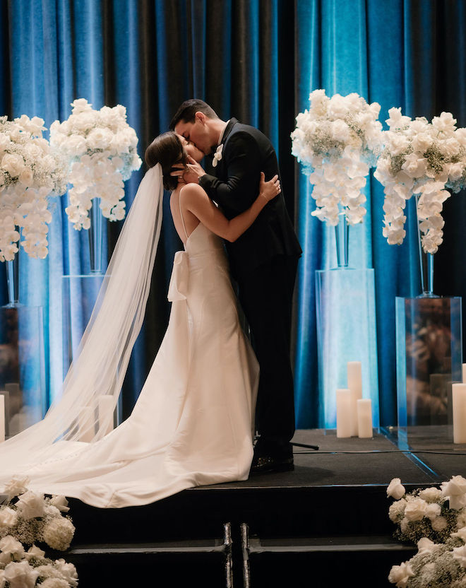 The bride and groom kissing at the altar. 