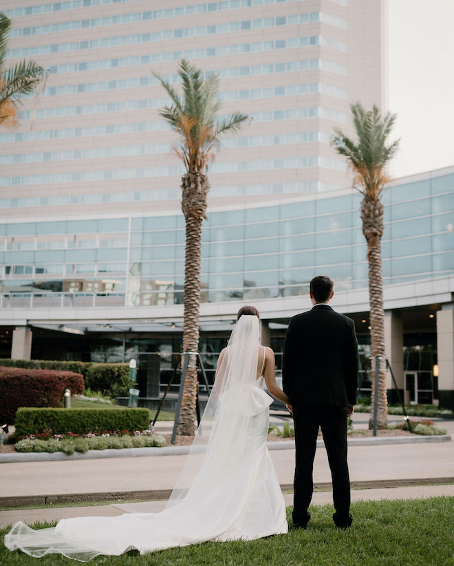 The bride and groom holding hands looking at The Royal Sonesta Houston Galleria. 