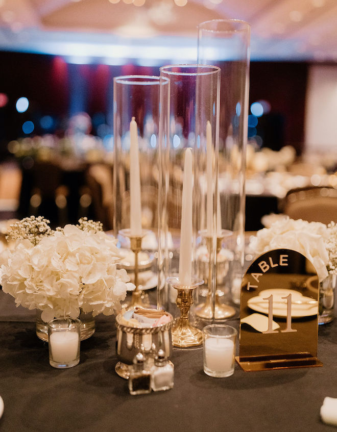 Pillar candles in acrylic candle holders with gold accents and white florals. 