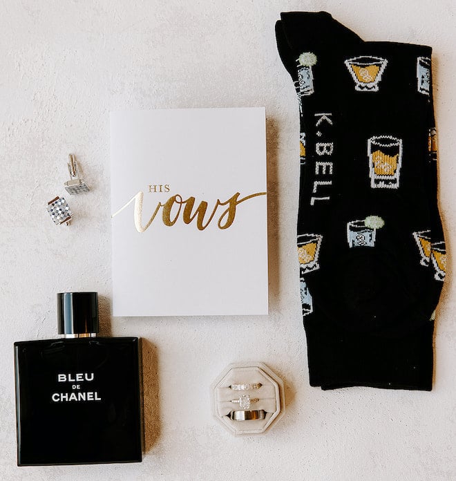 The grooms vows with a black Chanel cologne bottle, socks with cocktails on them, cufflinks and the couple's rings.