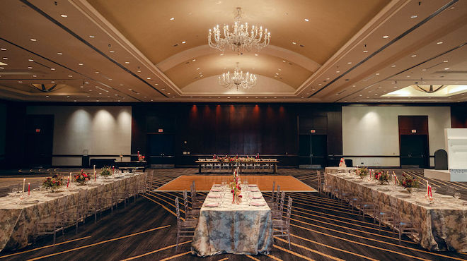 The ballroom at the Royal Sonesta Houston Galleria is detailed in pink florals, grey and pink linens and candle light for this wedding editorial. 