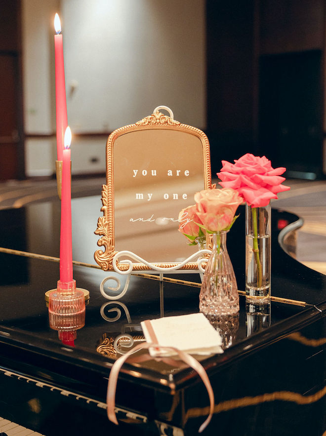 Pink candles, a decorative mirror and pink florals sit on top of a piano in the ballroom at the Royal Sonesta Houston Galleria. 