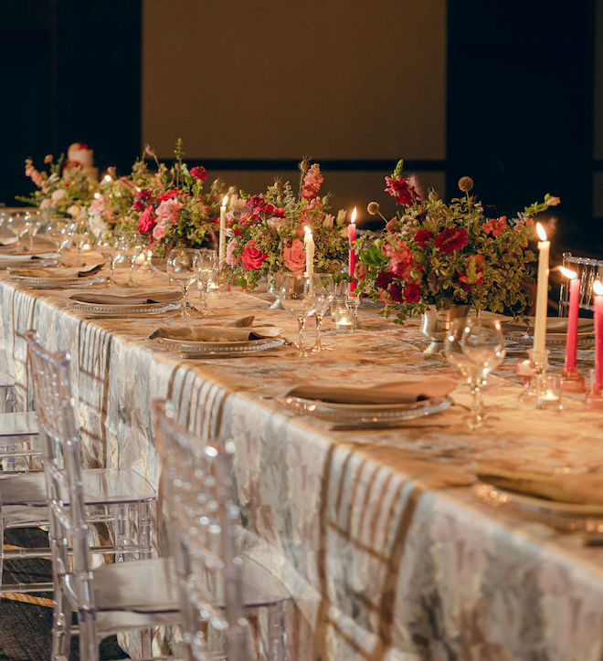 The reception tables are decorated in pink and grey linens, pastel florals, and warm candlelight. 