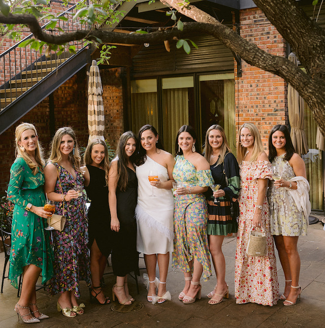 A bride posing with women wearing dressy casual dresses. 