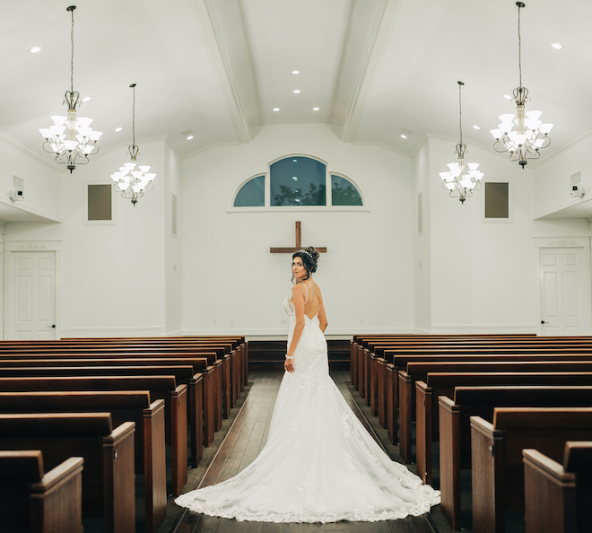 The bride walks down the aisle in the chapel at the wedding venue, Ashelynn Manor.