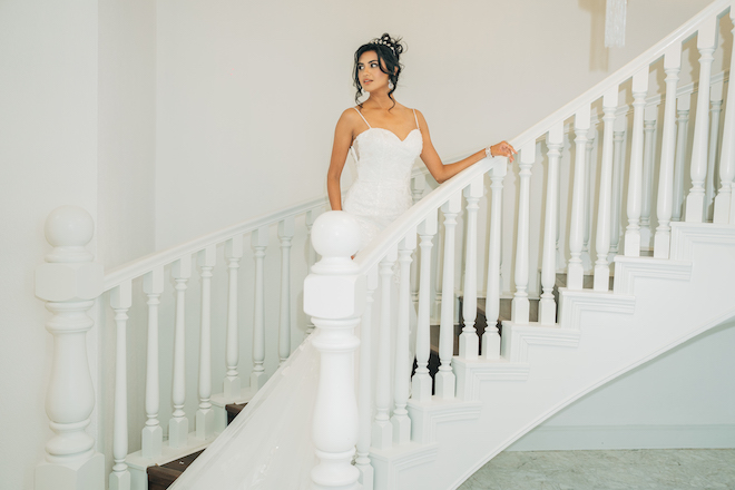 A bride walking up a white staircase at Ashleynn Manor.