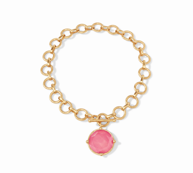 A gold necklace with a pink stone. 