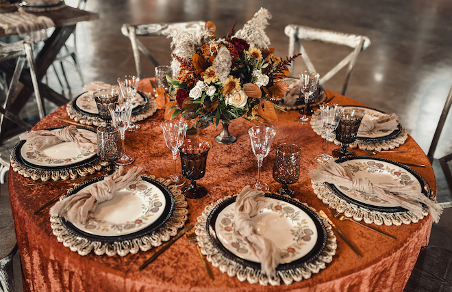 Burgundy, orange and cream-colored decor and florals detail tables for the autumn wedding editorial at Hummingbird Hill. 
