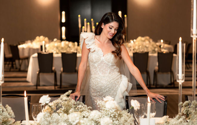 The model smiles while looking down at the reception tables in the ballroom at Hyatt Regency Baytown - Houston. 