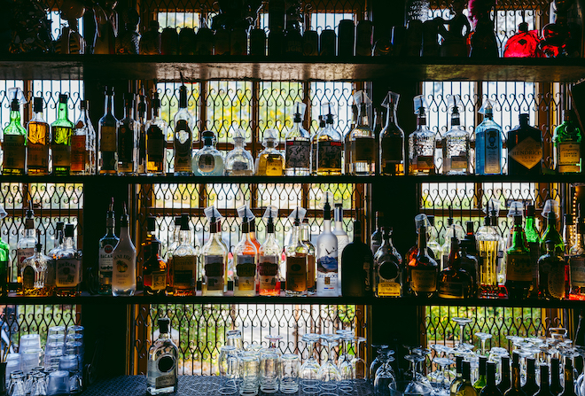 An assortment of alcohol line the shelves of the bar at the bride and groom's Houston wedding.